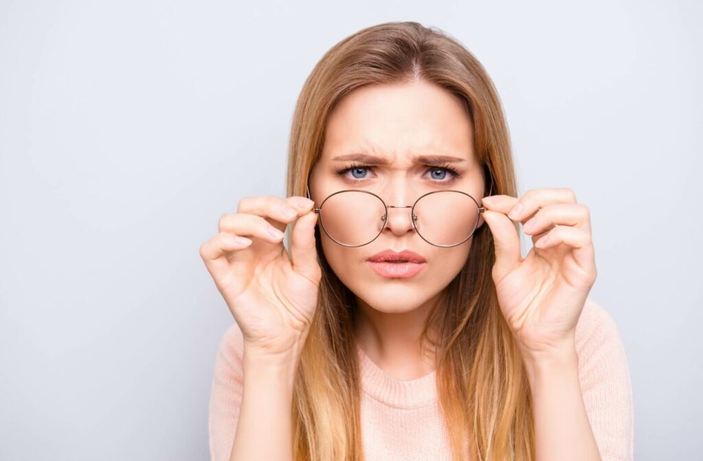 A young adult patient squinting their eyes while wearing glasses.