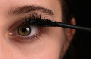 Close-up of a mascara brush applying makeup to eyelashes.